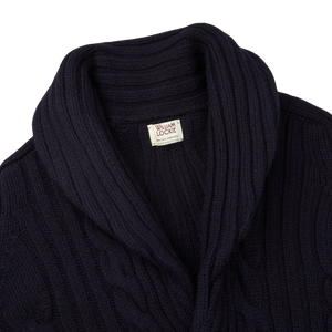 The William Lockie Navy Cable-Knit Lambswool Shawl Collar Cardigan, featuring a navy blue color and a cable-knit design, is displayed on a white background.