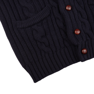 A Navy Cable-Knit Lambswool Shawl Collar Cardigan with buttons on the front manufactured by William Lockie.