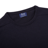 A William Lockie navy crewneck cashmere sweater with a label on the front.