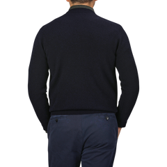 A person wearing a William Lockie Navy Crewneck Lambswool Sweater and blue pants is shown from the back, epitomizing a smart casual look. The background is gray.