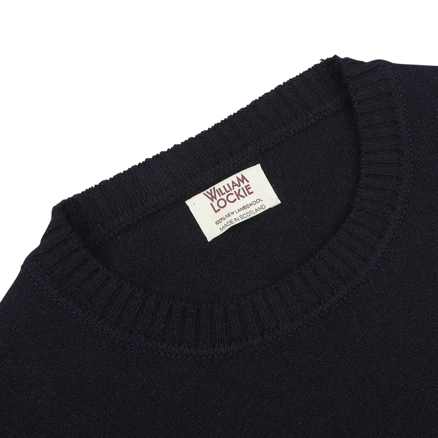 Close-up of a navy crew-neck lambswool sweater from William Lockie, with the label showing "WILLIAM LOCKIE Made in Scotland" sewn into the collar—perfect for smart casual occasions.