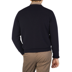 The back view of a man wearing a William Lockie Navy Lambswool Saddle Shoulder Cardigan and tan pants.