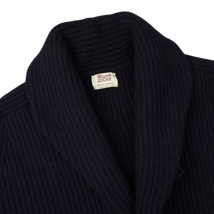 A Navy Lambswool Shawl Collar Cardigan made of Scottish lambswool with a label by William Lockie on the front.