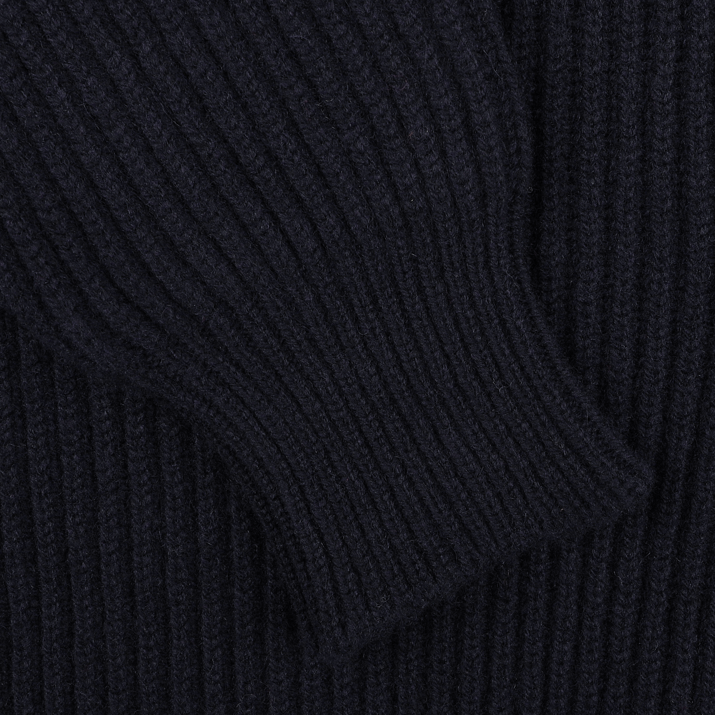 Close-up of the dark navy-colored, ribbed knit fabric of the William Lockie Navy Lambswool Shawl Collar Cardigan, showcasing a portion of a sleeve. The texture and quality of the Scottish lambswool are clearly visible.