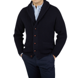 A man wearing a Navy Lambswool Shawl Collar Cardigan made by William Lockie with leather buttons.