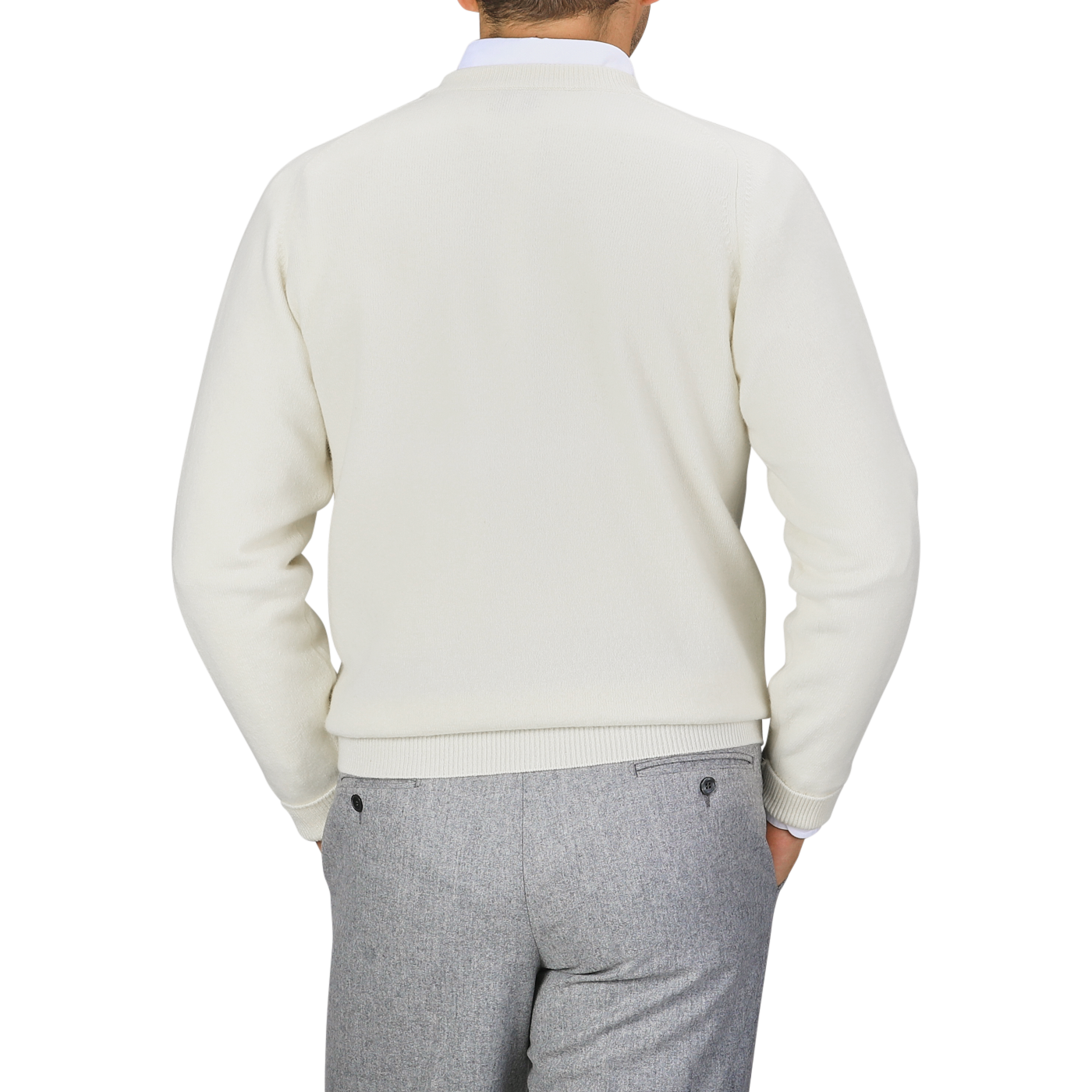 A person is wearing a William Lockie Off-White Deep V-Neck Lambswool Sweater and gray pants, standing with their back facing the camera against a plain background.