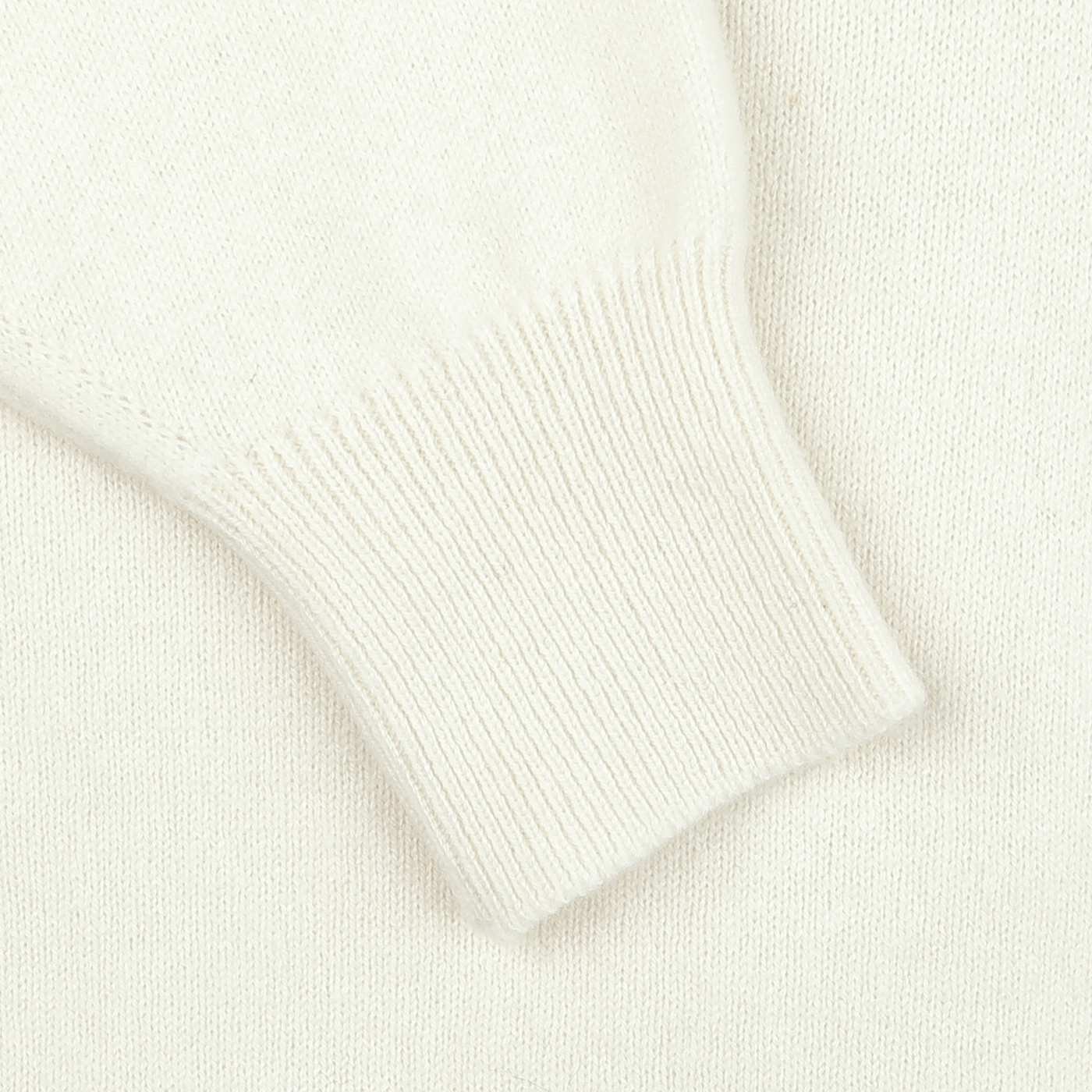 Close-up view of the Off-White Deep V-Neck Lambswool Sweater's sleeve with a ribbed cuff, designed by William Lockie.