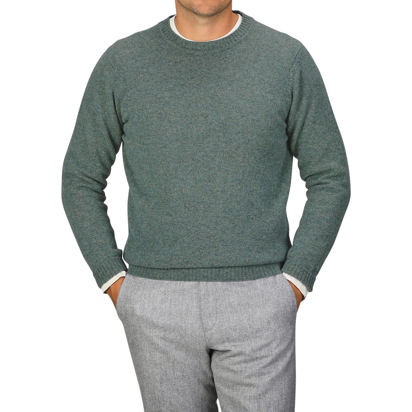 A person wearing a Peacock Crew Neck Lambswool Sweater by William Lockie and grey pants stands with hands in pockets against a plain grey background.