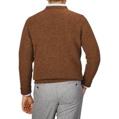 A person wearing a Pecan Brown Shetland Lambswool V-Neck Sweater by William Lockie and gray trousers is shown from the back against a plain background.