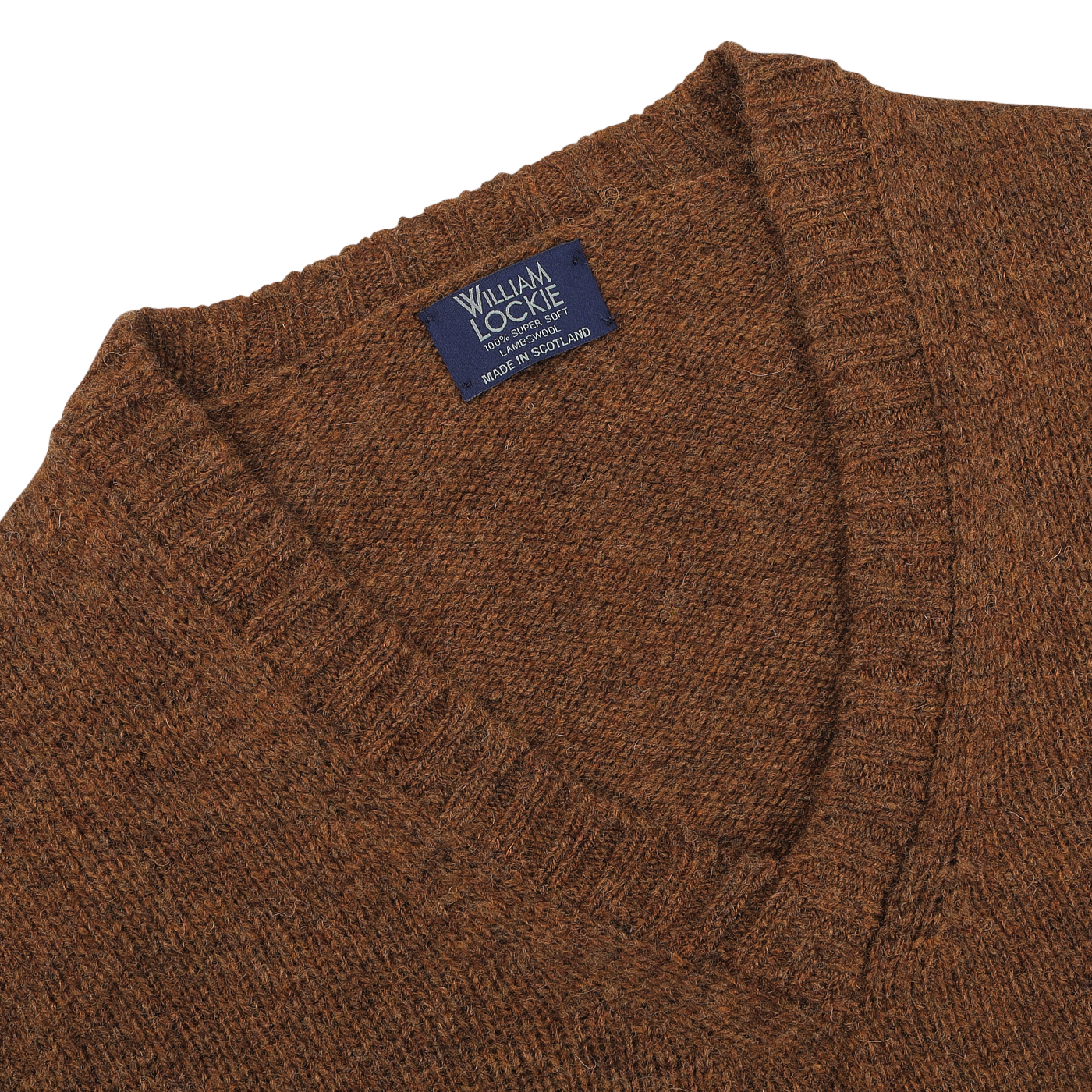 Close-up of a Pecan Brown Shetland Lambswool V-Neck Sweater with a "William Lockie" label that reads "Made in Scotland.