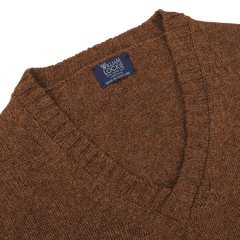 Close-up of a Pecan Brown Shetland Lambswool V-Neck Sweater with a "William Lockie" label that reads "Made in Scotland.