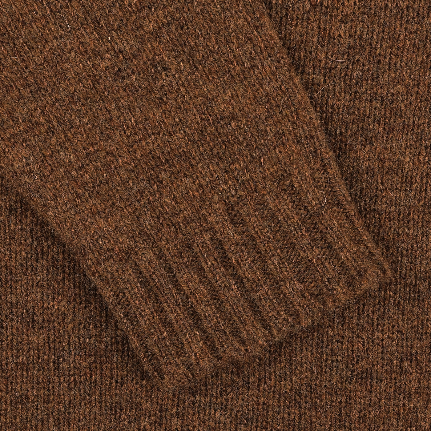 Close-up of a knitted brown wool texture, showing the detailed ribbed pattern of a William Lockie Pecan Brown Shetland Lambswool V-Neck Sweater.