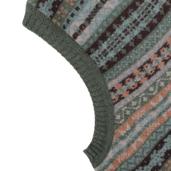 Close-up of the William Lockie Rosemary Green Fair Isle V-Neck Lambswool Slipover, featuring a multicolor geometric pattern in shades of green, blue, brown, and beige. Crafted from luxurious Scottish lambswool, it boasts a ribbed green hem for a perfect finishing touch.