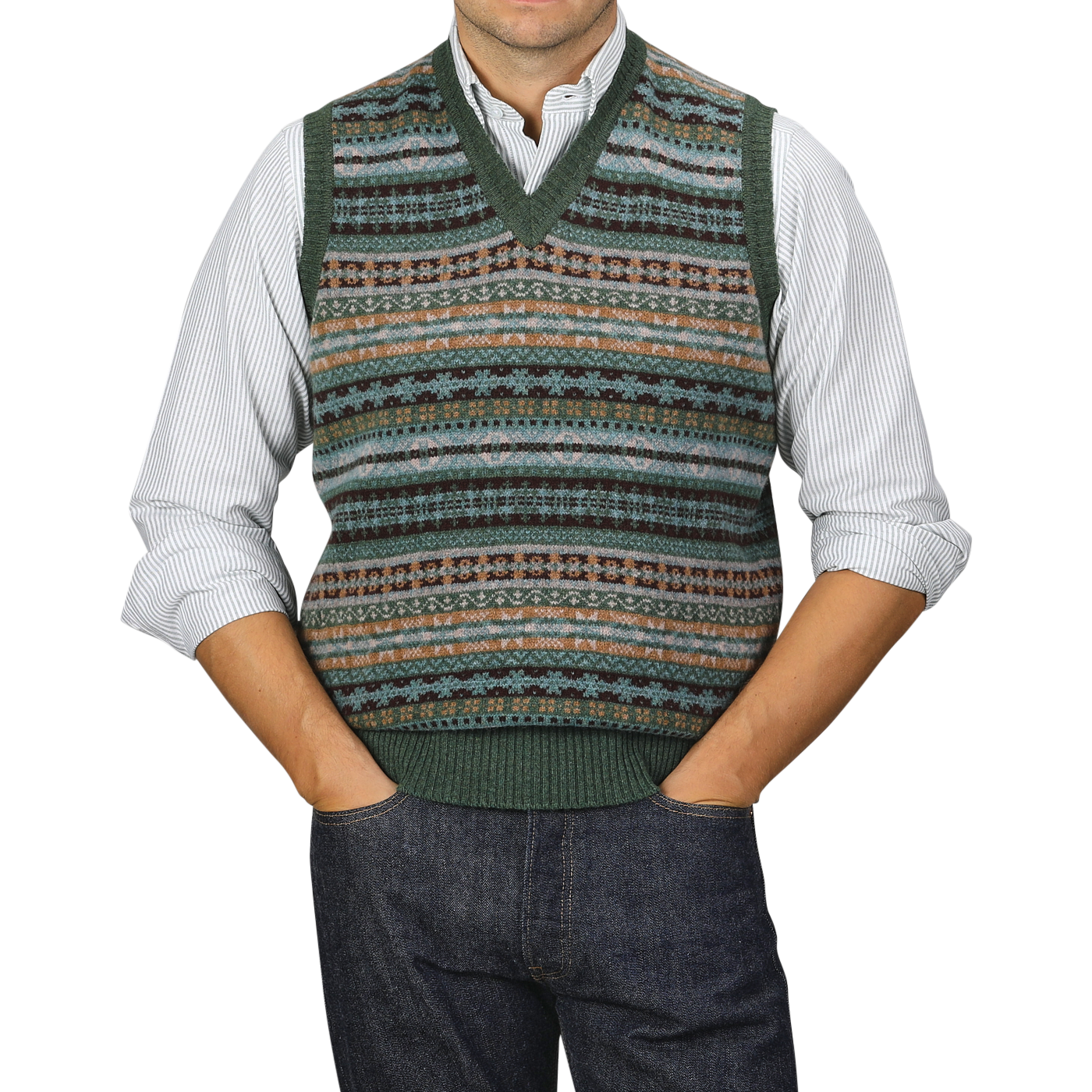 A person in a collared shirt and a William Lockie Rosemary Green Fair Isle V-Neck Lambswool Slipover, with hands in pockets, wearing jeans.