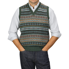 A person in a collared shirt and a William Lockie Rosemary Green Fair Isle V-Neck Lambswool Slipover, with hands in pockets, wearing jeans.