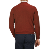 A man in a Sienna Brown William Lockie Crew Neck lambswool sweater and dark blue pants is shown from behind against a gray background.