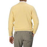 A person is shown from the back wearing a William Lockie Solar Yellow Deep V-Neck Lambswool Sweater and gray pants.