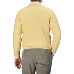 A person is shown from the back wearing a William Lockie Solar Yellow Deep V-Neck Lambswool Sweater and gray pants.