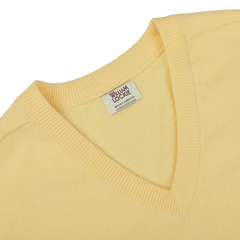 Close-up of a Solar Yellow Deep V-Neck Lambswool Sweater with a visible "William Lockie" label inside the collar.