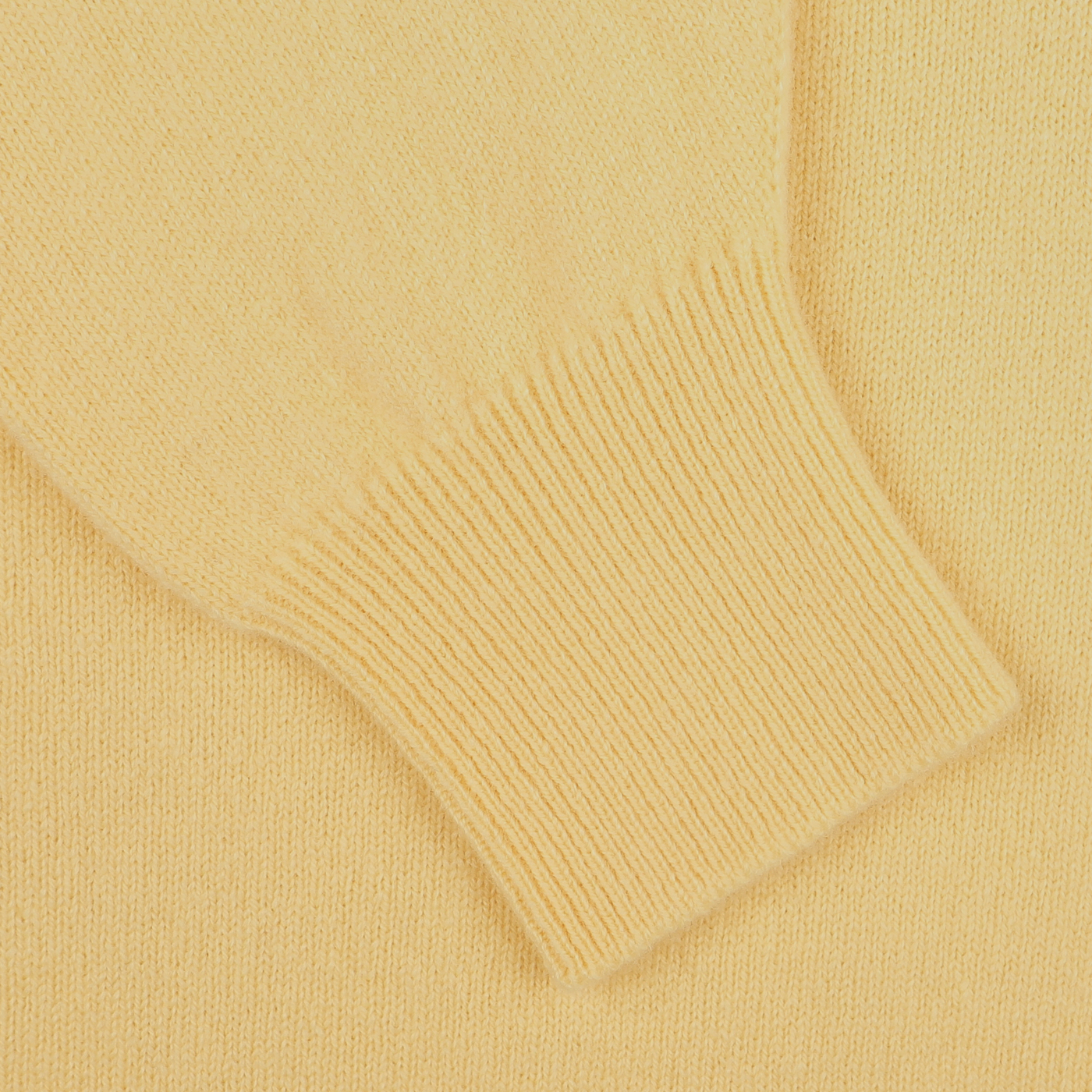 Close-up of the Solar Yellow Deep V-Neck Lambswool Sweater by William Lockie, showing the sleeve cuff and part of the body, illustrating the texture and stitching details.