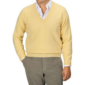 A person wearing a William Lockie Solar Yellow Deep V-Neck Lambswool Sweater over a white collared shirt and gray pants, posed against a neutral background.