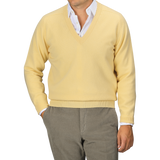 A person wearing a William Lockie Solar Yellow Deep V-Neck Lambswool Sweater over a white collared shirt and gray pants, posed against a neutral background.