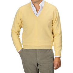 A person wearing a William Lockie Solar Yellow Deep V-Neck Lambswool Sweater over a white collared shirt and gray pants, posed against a neutral background.