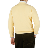 The back view of a man wearing a William Lockie Solar Yellow Lambswool Saddle Shoulder Cardigan.