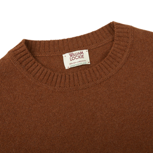 A warm Spaniel Brown Crew Neck Lambswool Sweater made of Scottish lambswool with a label on it. (Brand: William Lockie)