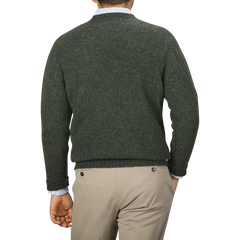 A person facing away, wearing the Spruce Brushed Wool Shetland Lambswool V-Neck sweater by William Lockie and beige pants, stands against a neutral background, showcasing chic knitwear fashion.