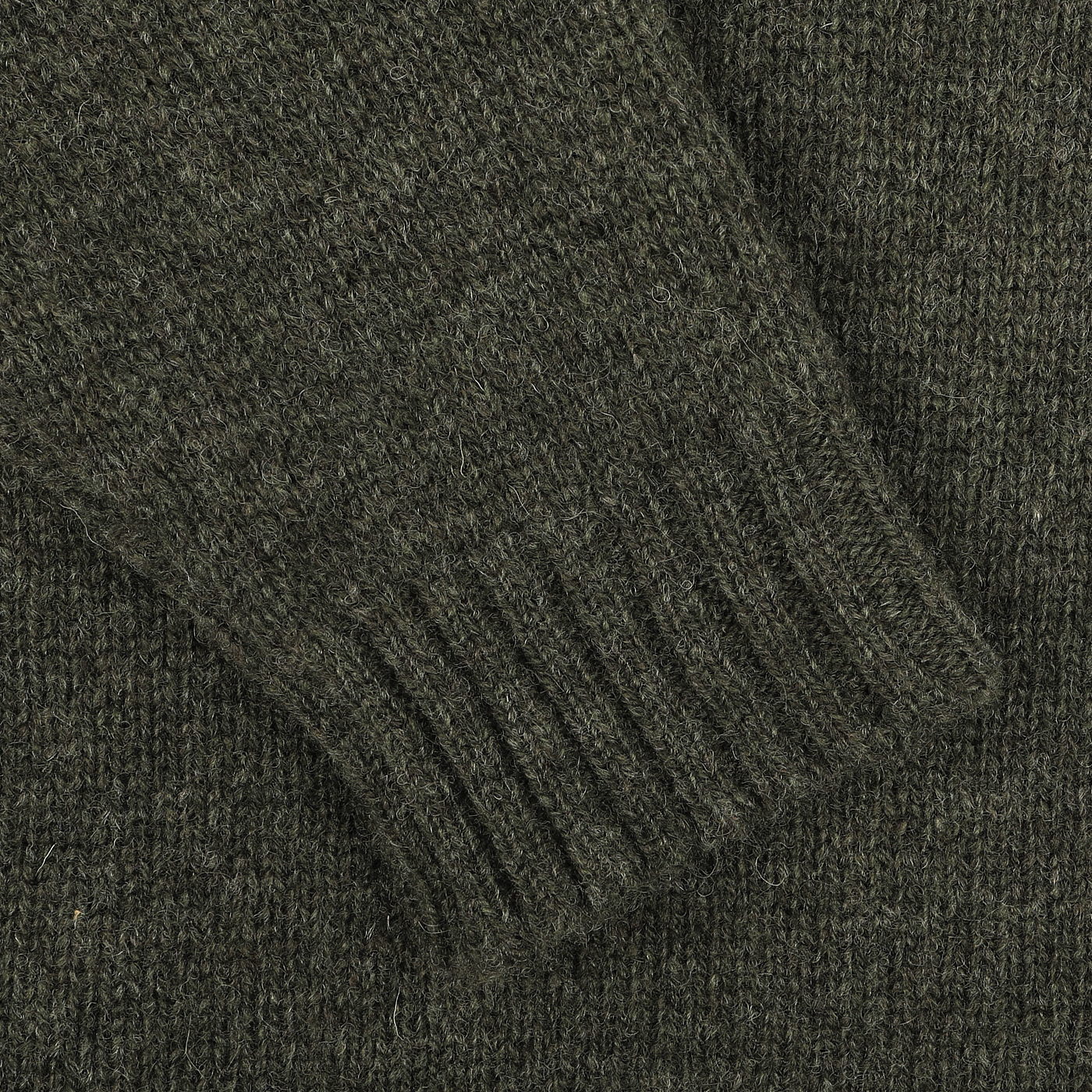 Close-up of a William Lockie Spruce Green Shetland Lambswool V-Neck Sweater sleeve, showcasing the ribbed cuff detail.