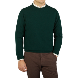 A man wearing a Tartan Green Crew Neck Lambswool Sweater by William Lockie and brown pants.