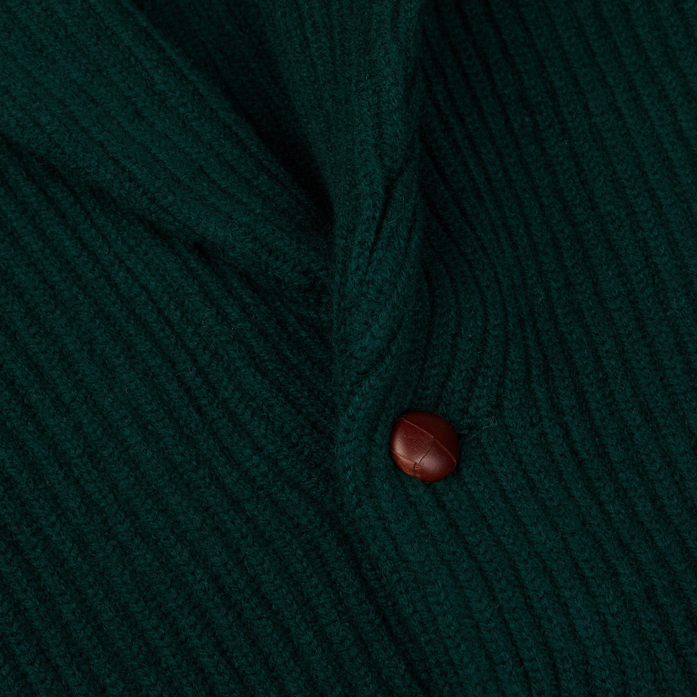 A close up of a Tartan Green Lambswool Shawl Collar Cardigan by William Lockie with a wooden button.