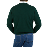 The back view of a man wearing a William Lockie Tartan Green Lambswool V-Neck Sweater and jeans.