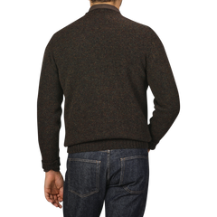 A person wearing a William Lockie Turin Brushed Shetland Lambswool Crew Neck sweater in brown and blue jeans is shown from the back against a plain gray background.