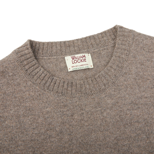 A comfy William Lockie Vole Beige Crew Neck Lambswool Sweater with a label on it.