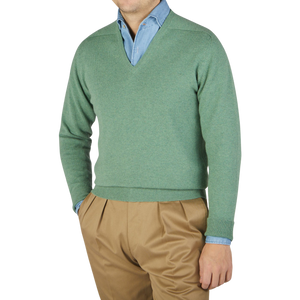 A man wearing a William Lockie Green Mix V-Neck Cashmere Sweater made of Scottish cashmere and khaki pants.