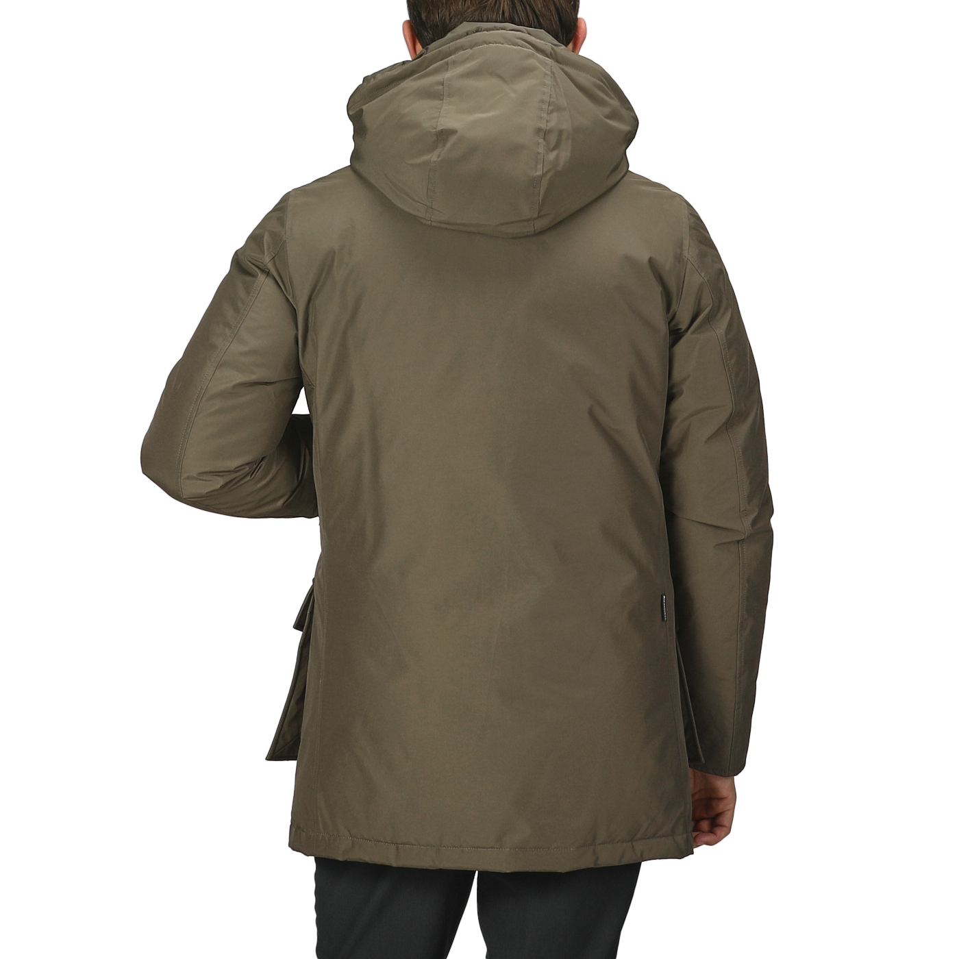 An individual wearing a dark green, waterproof Arctic Parka by Woolrich is depicted from behind against a plain gray background.