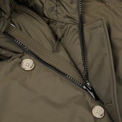 Close-up of a Dark Green Stretch Nylon Arctic Parka by Woolrich, featuring a zipper and beige buttons, made with waterproof fabric.