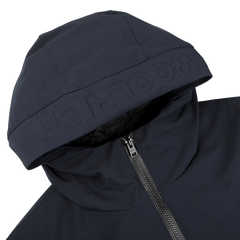 A close-up of the Woolrich Melton Blue Pacific Soft Shell Jacket showcases a visible zipper and embossed branding on the hood. The sleek, dark design conveys modernity and functionality, making it perfect for any adventure.