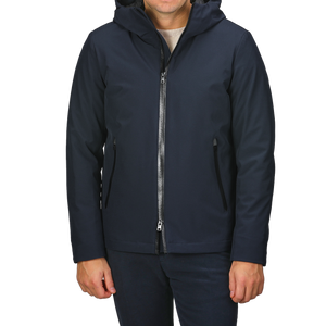 A person wearing a Melton Blue Pacific Soft Shell Jacket from Woolrich, featuring a front zipper and pockets, standing against a light gray background.