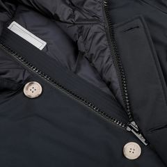 Close-up of a navy blue Melton Blue Stretch Nylon Arctic Parka by Woolrich, showcasing tan buttons, a visible zipper, and quilted lining, featuring waterproof outer fabric for enhanced weather protection.