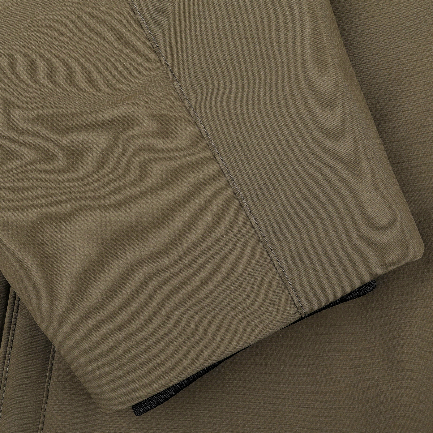 The image captures a close-up view of the military green fabric, highlighting its visible stitching and folded edges, which evokes the sleek design of the Woolrich Military Green Stretch Nylon Hood Jacket.