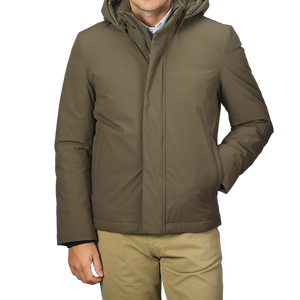 A person wearing a military green stretch nylon hood jacket by Woolrich and khaki pants stands against a plain background.