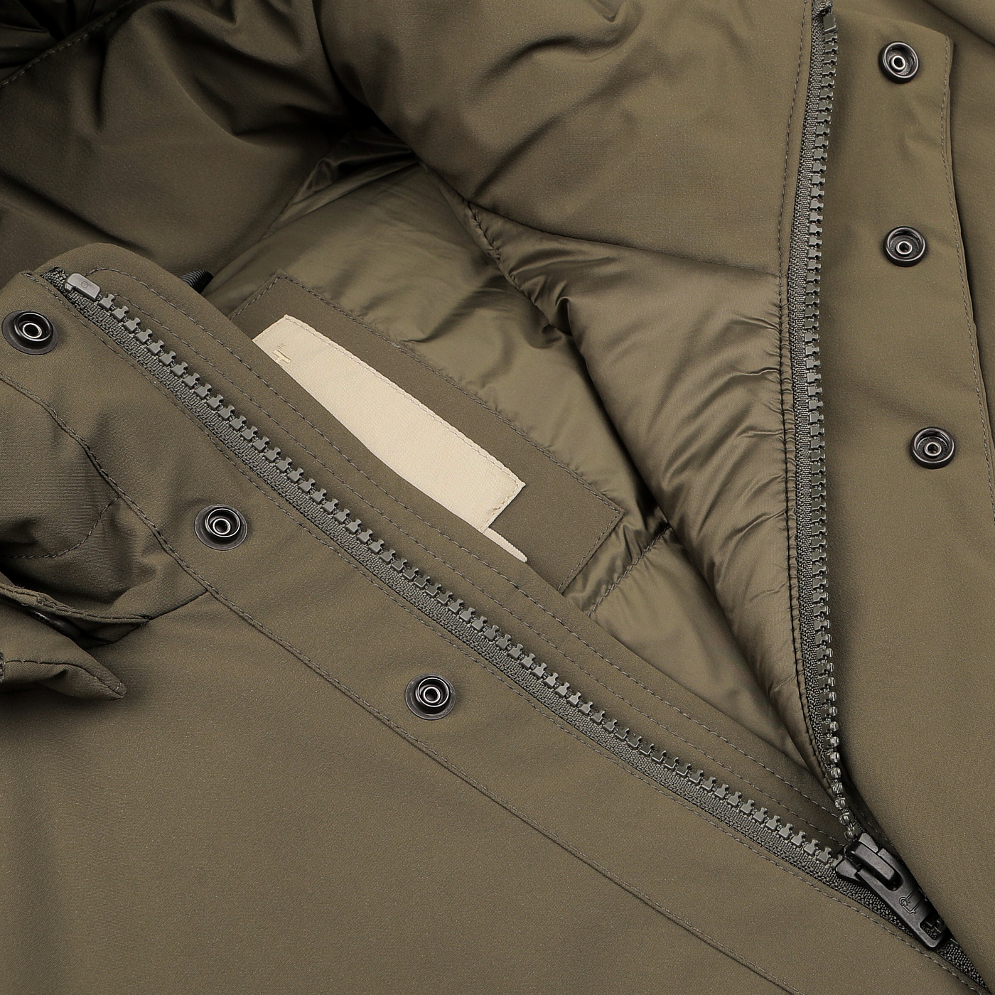 Close-up of a Military Green Stretch Nylon Hood Jacket by Woolrich, featuring its unzipped front that reveals the inner lining of this waterproof, windproof piece and a beige rectangular label inside.