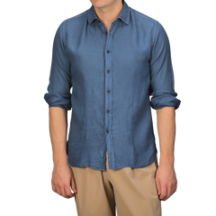 A person wearing a Dark Blue Washed Linen Legacy Shirt by Xacus with rolled-up sleeves and beige pants.