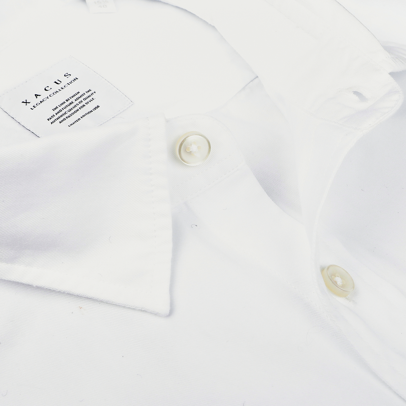 Close-up of a neatly folded White Cotton Twill Legacy Shirt by Xacus, showcasing its slim fit design with visible buttons and a label on the interior collar.