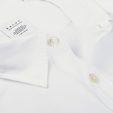 Close-up of a neatly folded White Cotton Twill Legacy Shirt by Xacus, showcasing its slim fit design with visible buttons and a label on the interior collar.