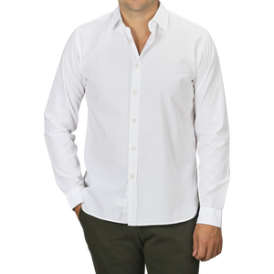 A person wearing a slim fit White Cotton Twill Legacy Shirt by Xacus and dark green pants stands with one hand in their pocket. The individual's face is not visible.