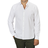 A person wearing a slim fit White Cotton Twill Legacy Shirt by Xacus and dark green pants stands with one hand in their pocket. The individual's face is not visible.